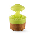 Wood grain green rain cloud shaped humidifier diffuser with coloured LED light on a table.