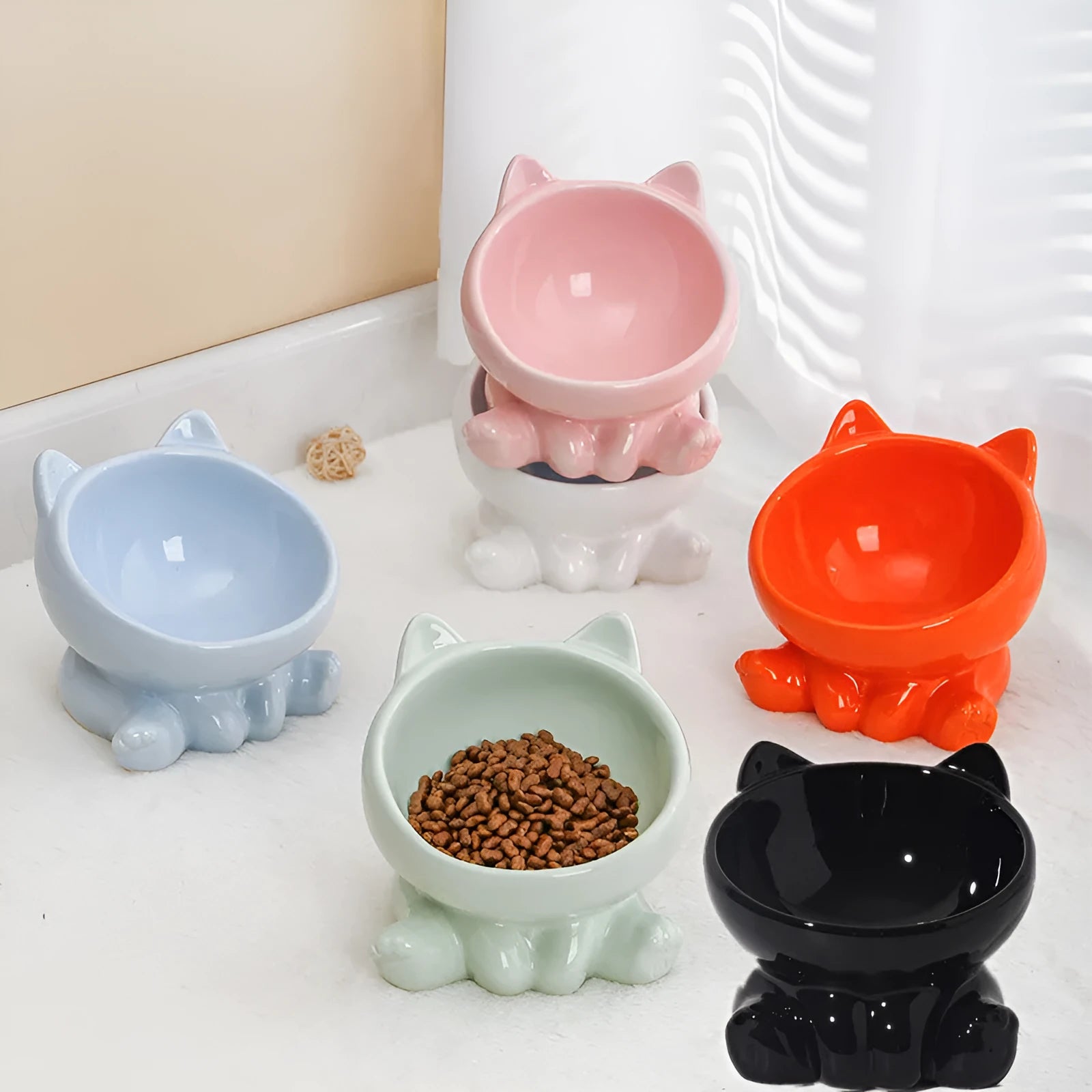 Ceramic cat bowl with neck guard in black and white and pink and blue colour options on a white background