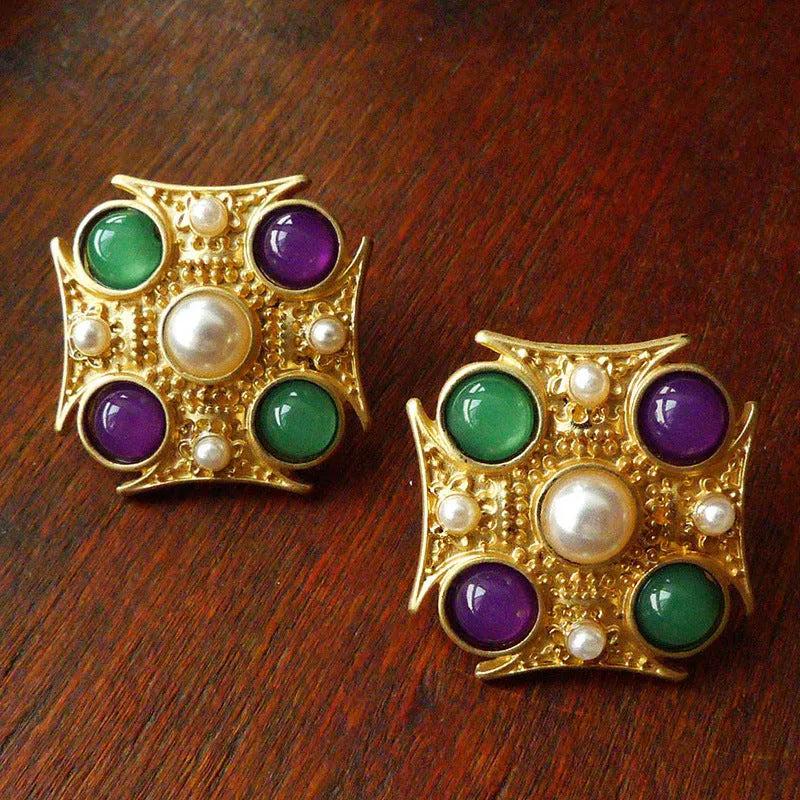 Close-up of a vintage baroque style zinc alloy brooch with a diamond shape on a dark fabric background.