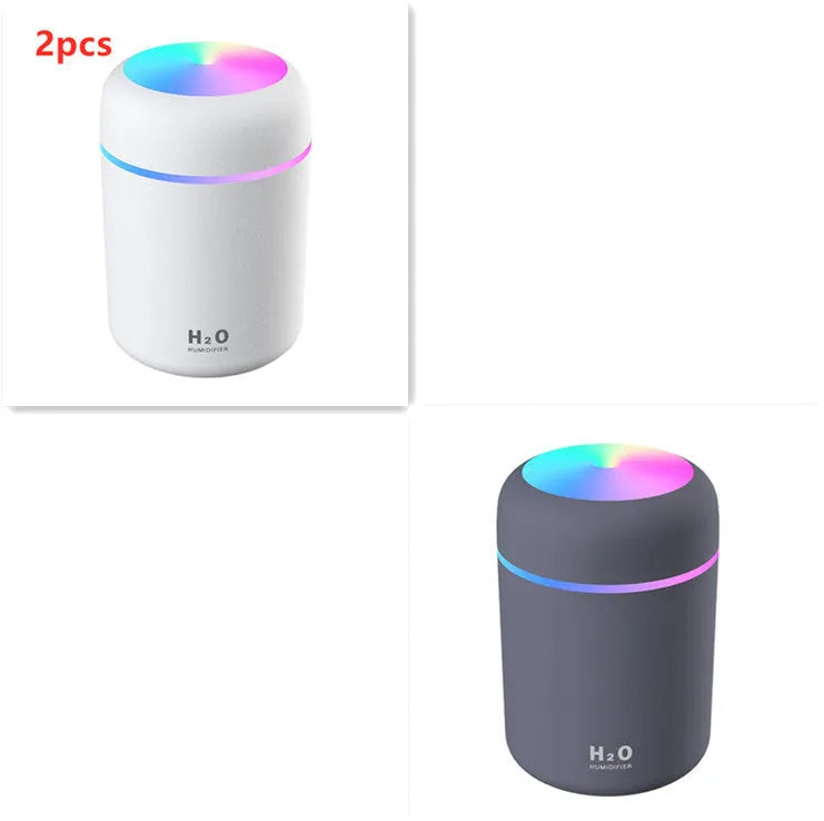 Pink USB desktop humidifier with coloured lights and water tank on a wooden desk