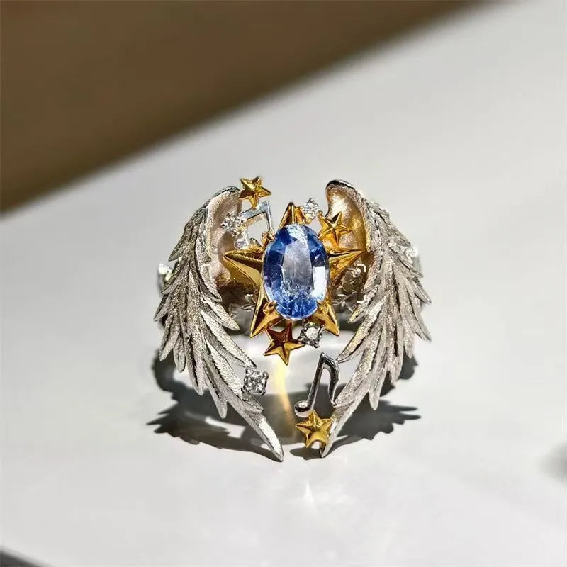 Gold-tone geometric angel wings alloy ring with adjustable opening on a finger.