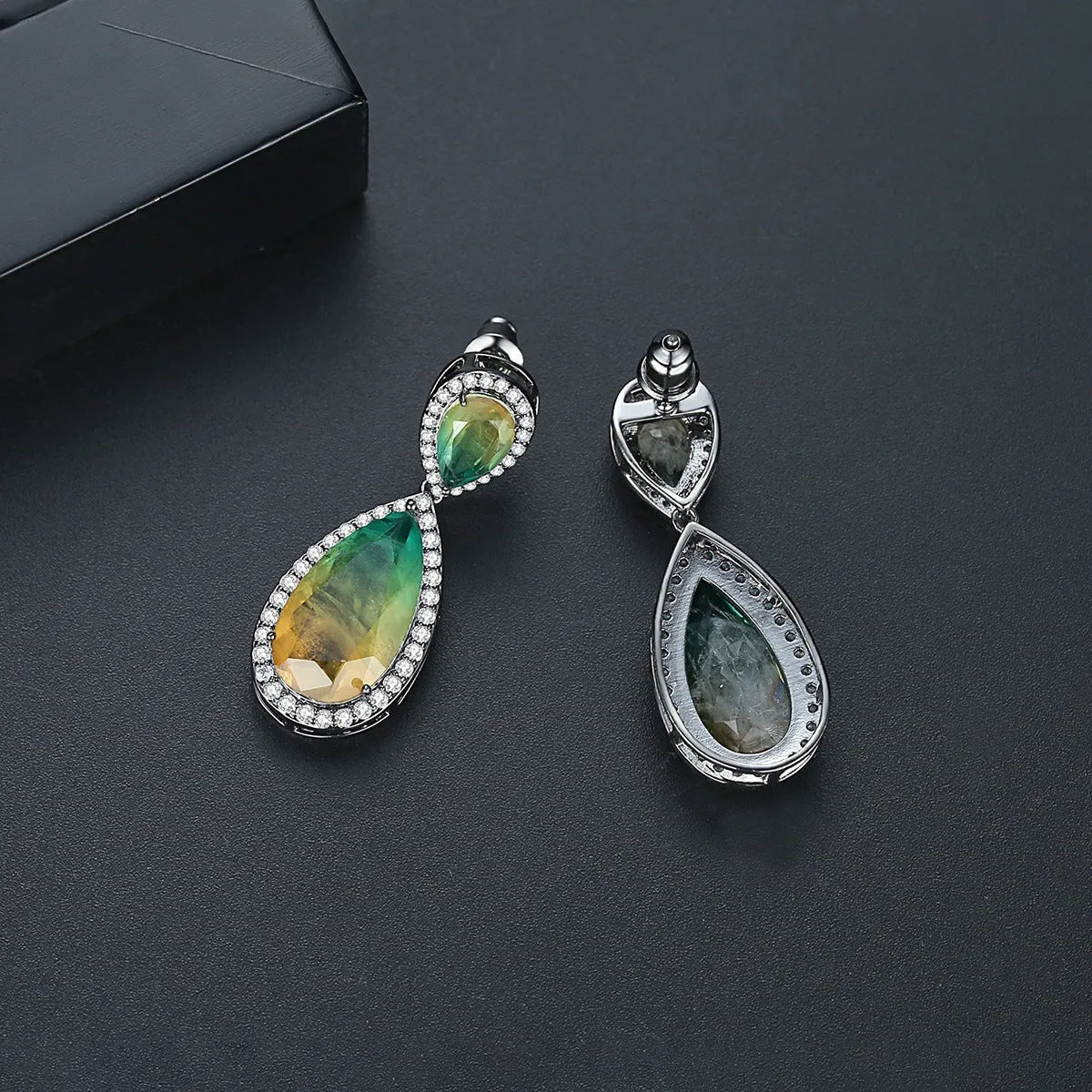 Drop shape copper earrings with inlaid synthetic gemstone in blue colour option on a white background