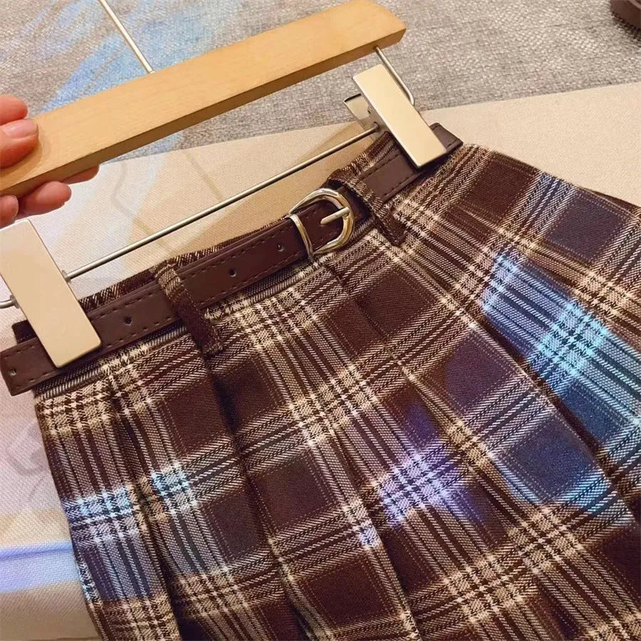 Girls' red and black plaid pleated A-line skirt on a hanger, showing cotton lining.