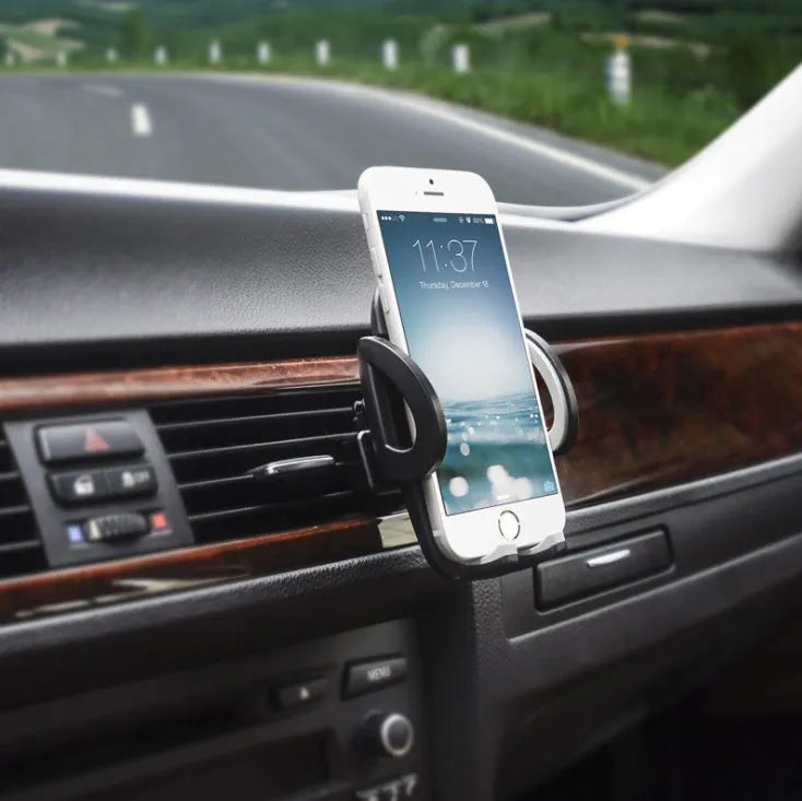 Black plastic mobile phone holder mounted on car air conditioning outlet with phone inserted