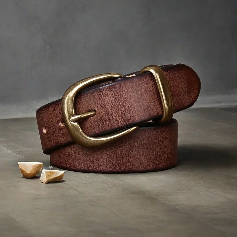 Men's black genuine cowhide leather belt with copper pin buckle on a jeans background.
