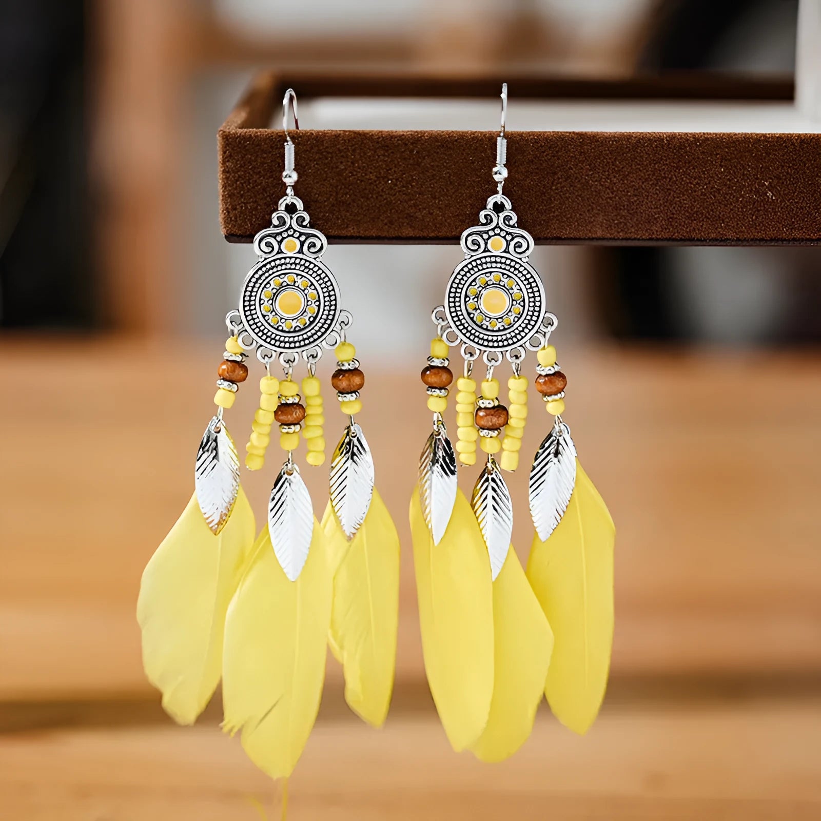 A pair of bohemian-style round drop earrings with a feather leaf pattern, shown in one of thirteen available colours.