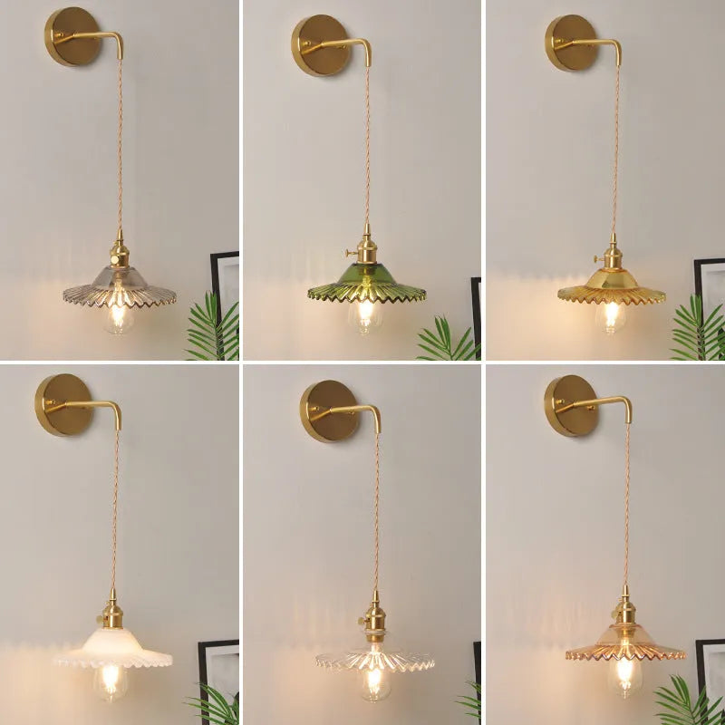 Brass lotus-shaped wall lamp with glass shade in choice of six colours on a plain wall.