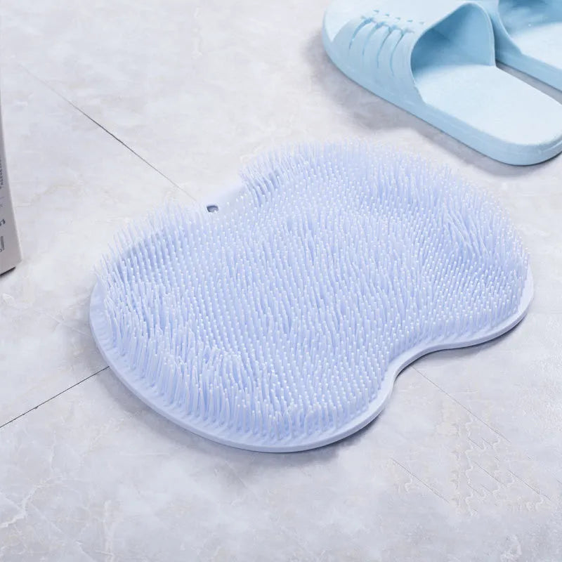 Orange silicone bath massage brush mat with suction cups on a bathroom floor