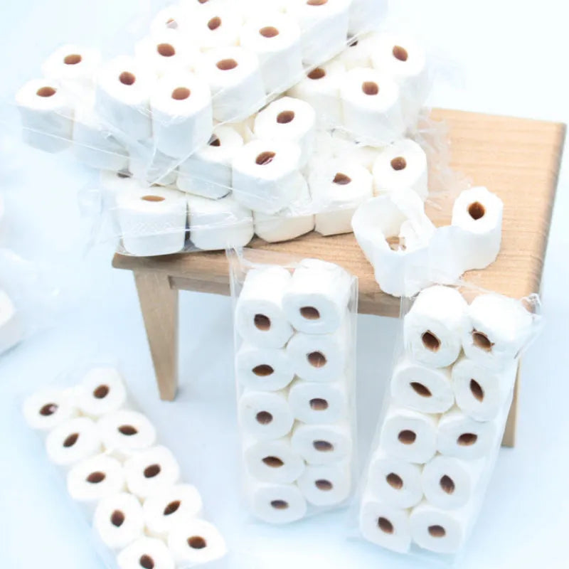 Small-scale simulated toilet paper roll model made of paper, shown next to a ruler for scale.