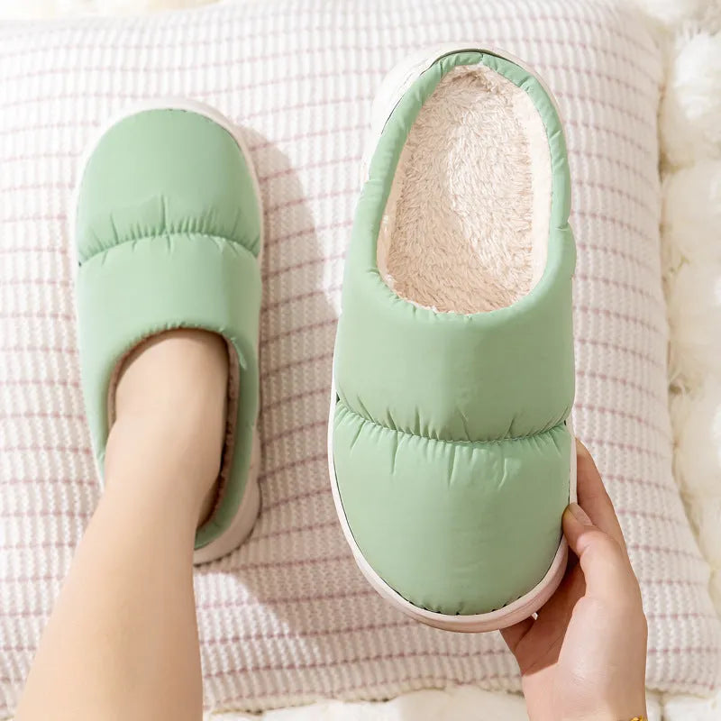 Blue down cotton indoor slippers with thick rubber sole and plush lining, shown on a wooden floor.
