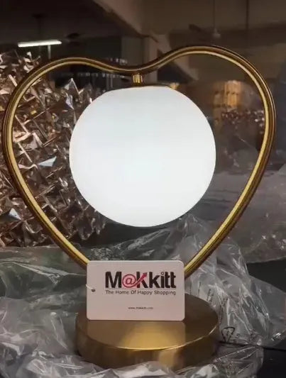 Clear acrylic heart shaped LED table lamp with warm white light on a surface.