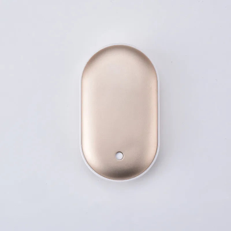Compact rose gold USB rechargeable hand warmer and power bank with digital display on a wooden table.