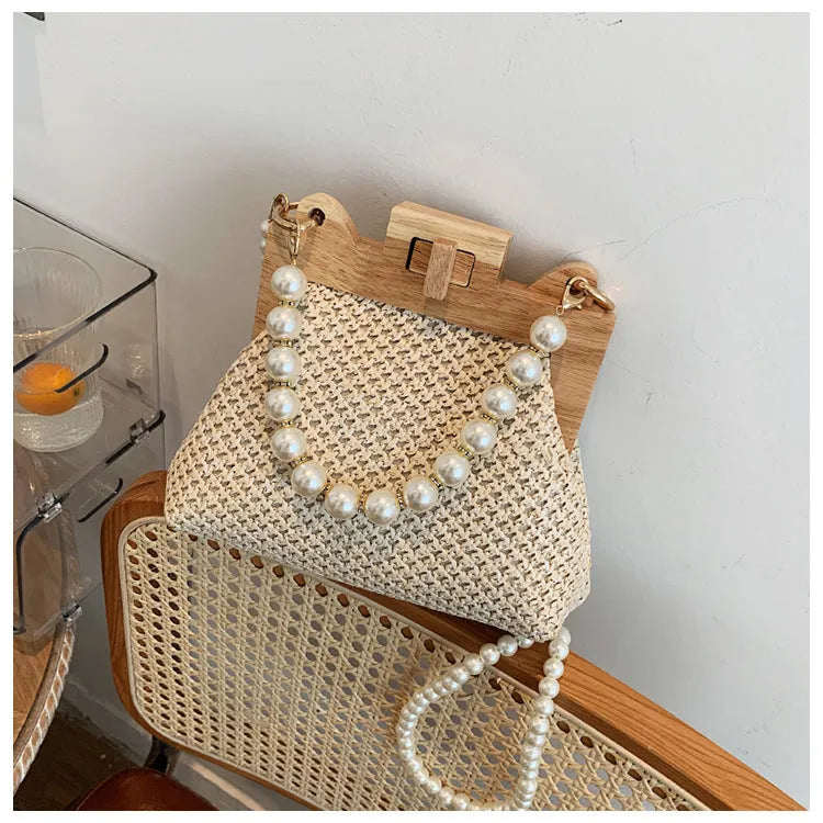 Women's woven straw shoulder bag with pearl chain detail in beige colour, showing interior organiser pockets.