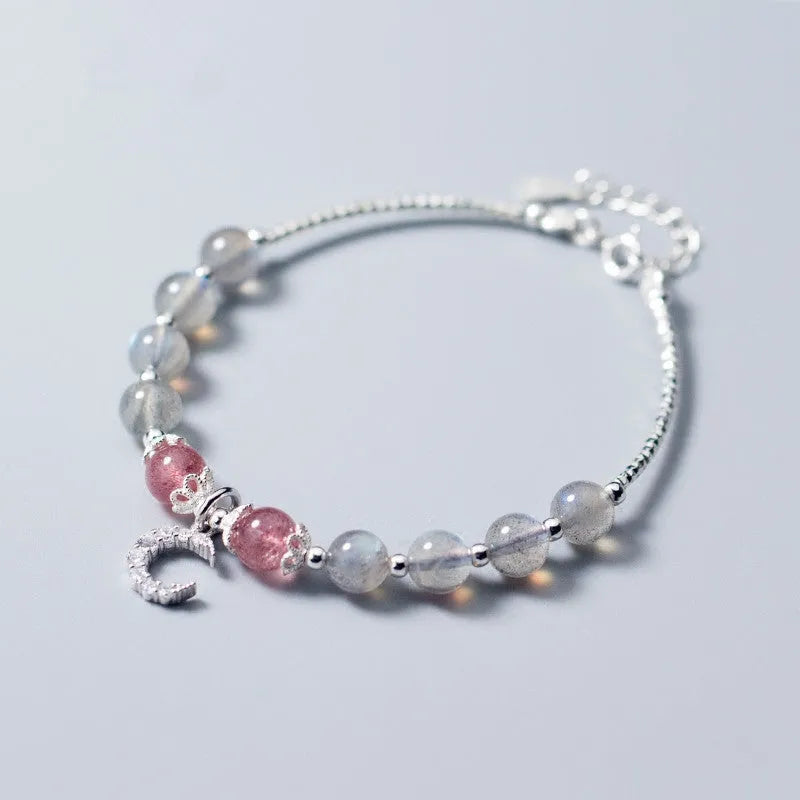 Natural moonstone bracelet with silver crescent moon charm on an adjustable chain.