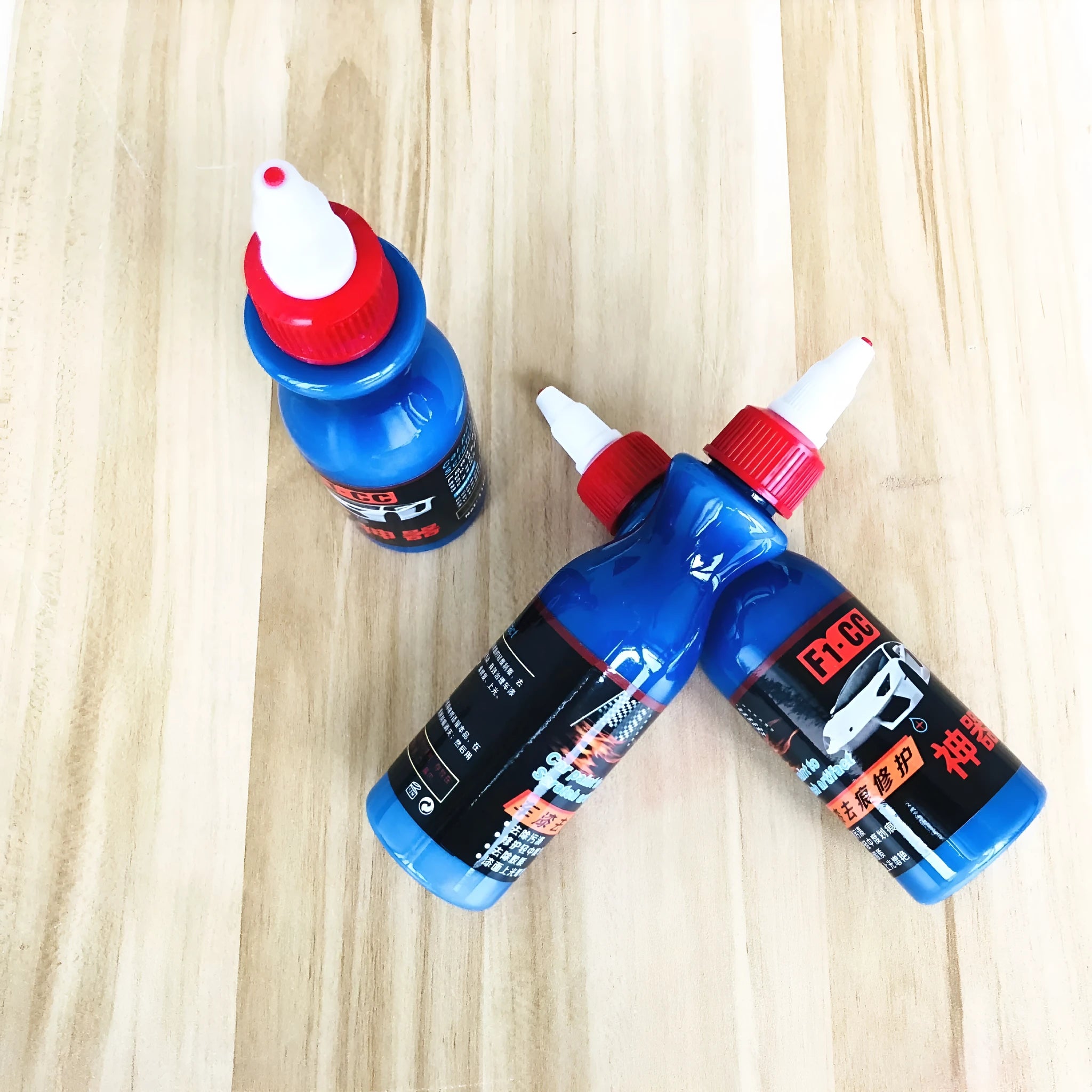 Small blue container of scratch repair agent with integrated wiping tool for automotive paint