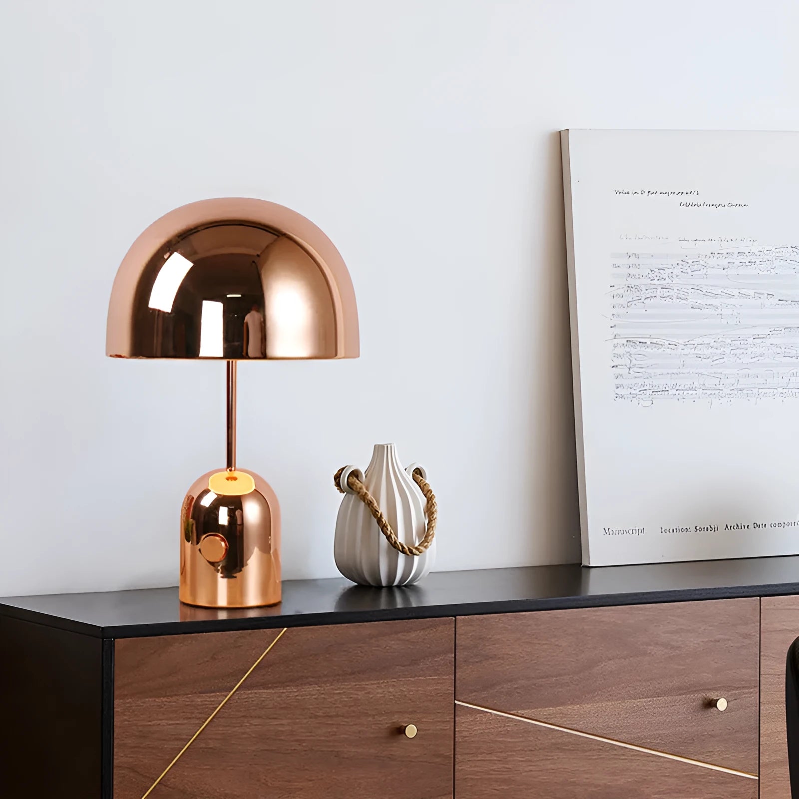 Mushroom-shaped table lamp with a metal base in rose gold finish on a wooden surface.