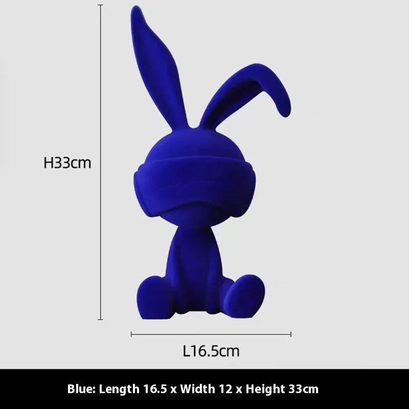 Suede blindfold rabbit resin table ornament in blue, green, or red colour on a shelf.