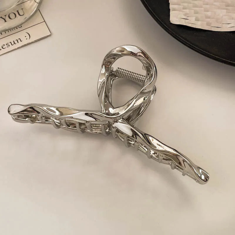 Assortment of silver metal hair claw barrettes with various designs including bows, pearls, and geometric shapes.
