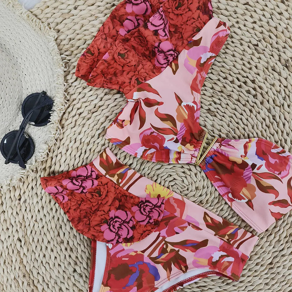 Red floral print on pink women's one-shoulder ruffled bikini with high-waist bottoms.