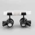 White head mounted magnifying glass with LED light, shown in unfolded position for use on a workbench.