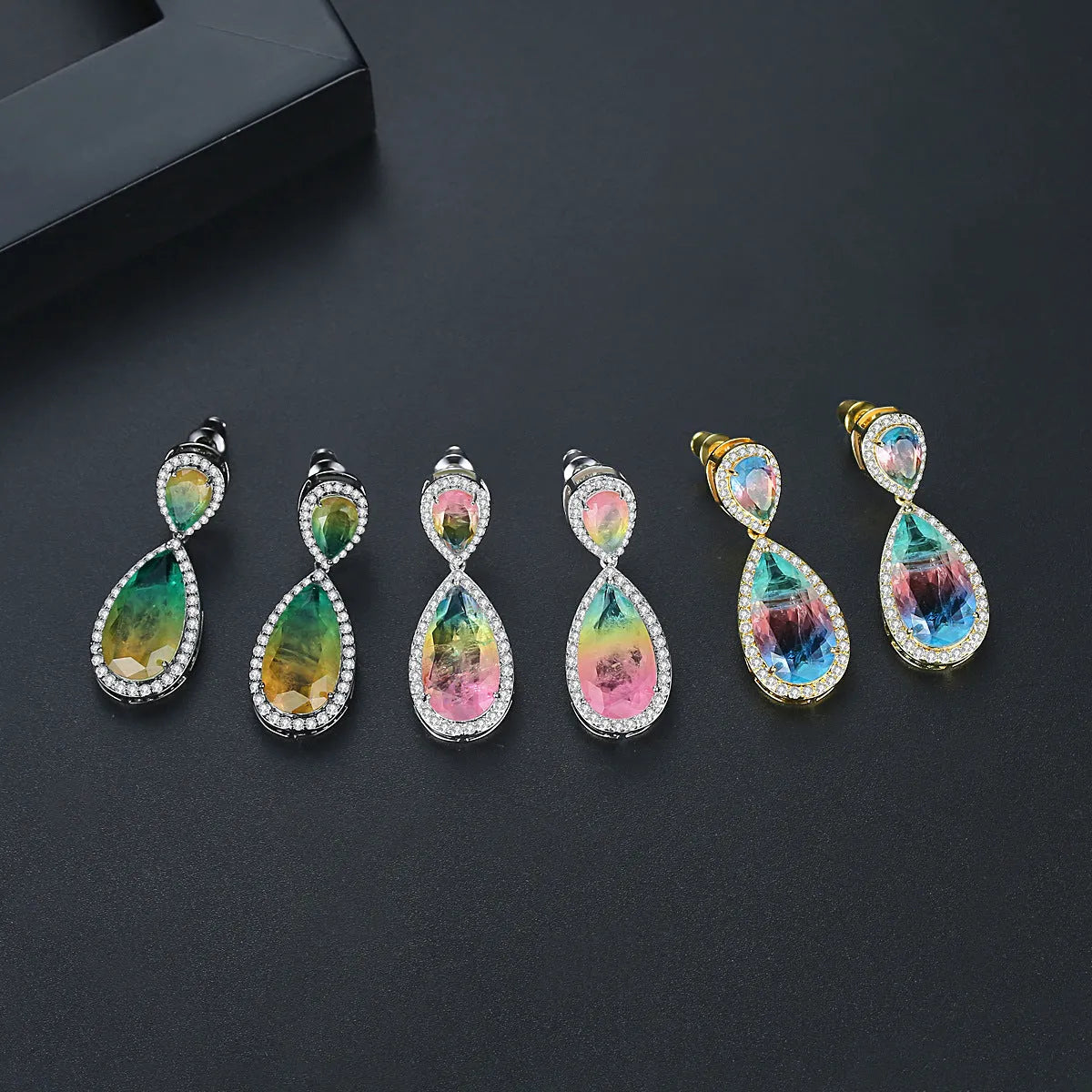 Drop shape copper earrings with inlaid synthetic gemstone in blue colour option on a white background