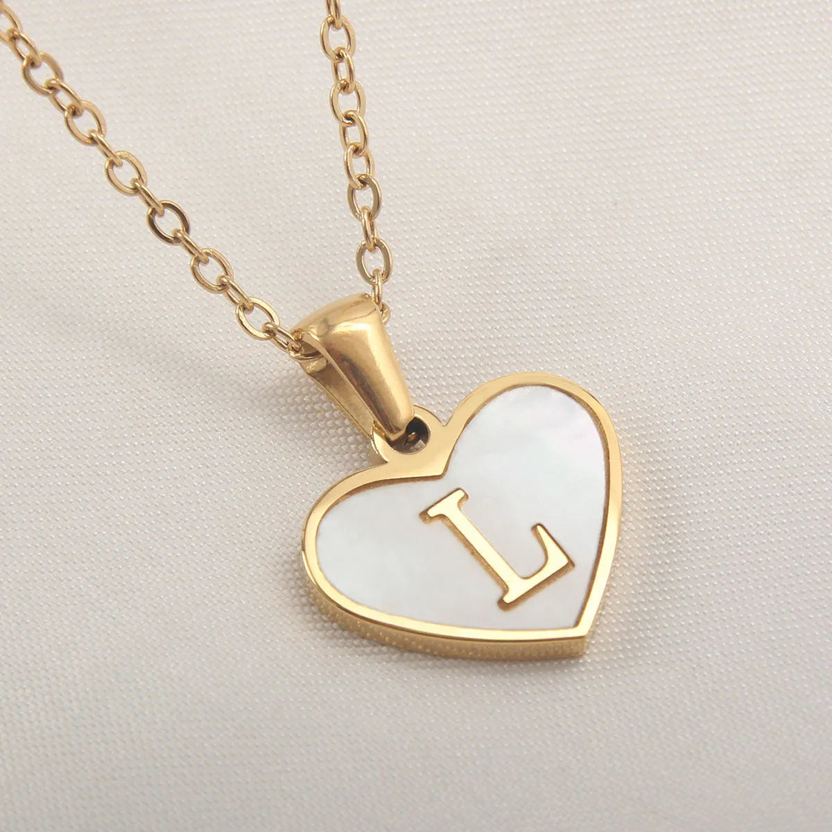 Gold plated heart-shaped white shell pendant personalised initial necklace on a stainless steel chain.
