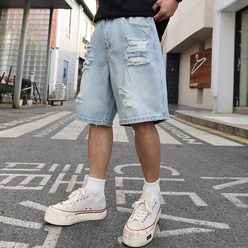 Light blue ripped denim shorts with distressed details, loose straight leg cut on a neutral background.
