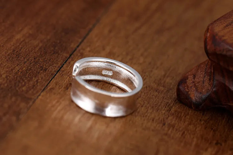 Geometric open ring with adjustable size in frosted sterling silver on a grey background.