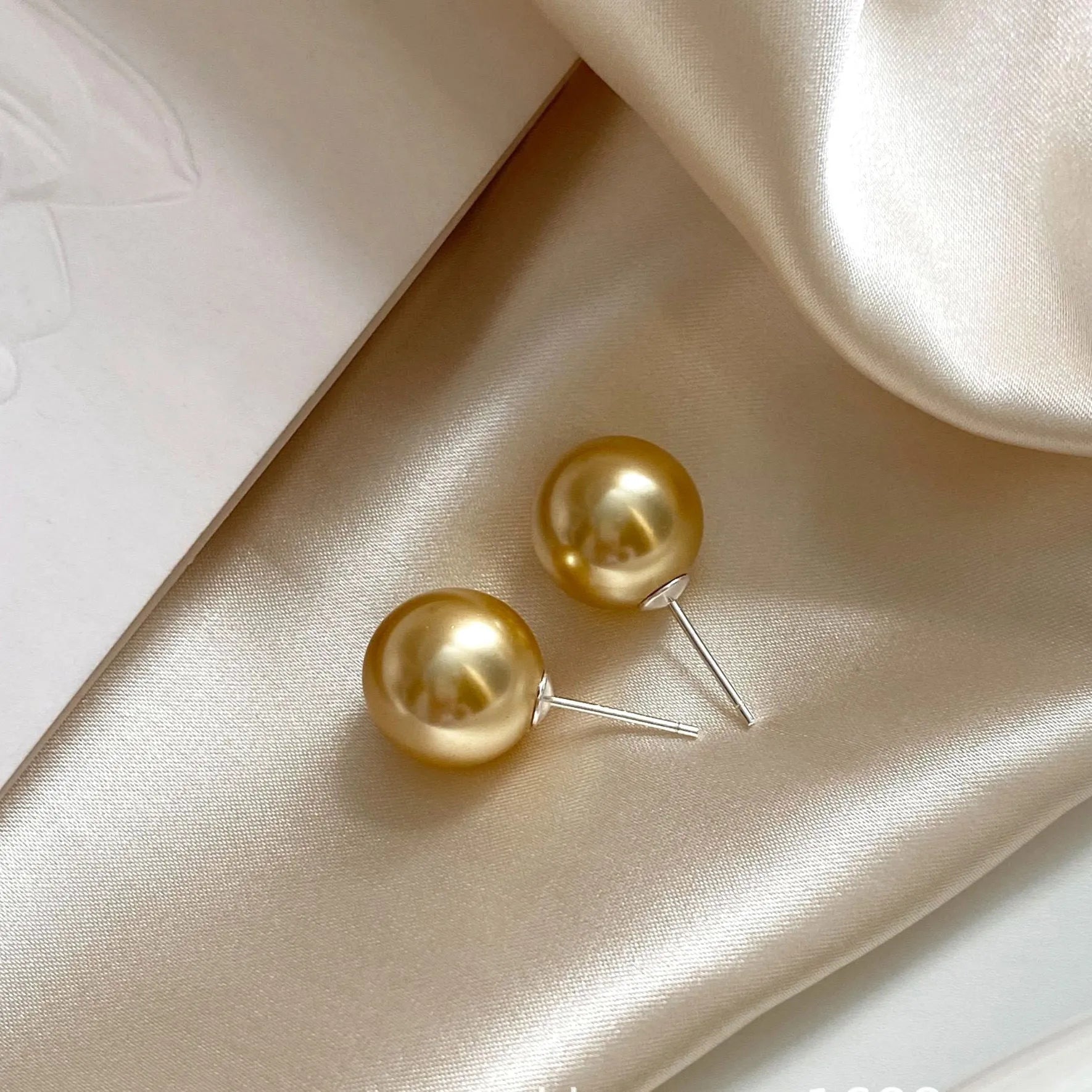 A pair of large geometric pearl stud earrings with an eight-point star detail on silver settings.