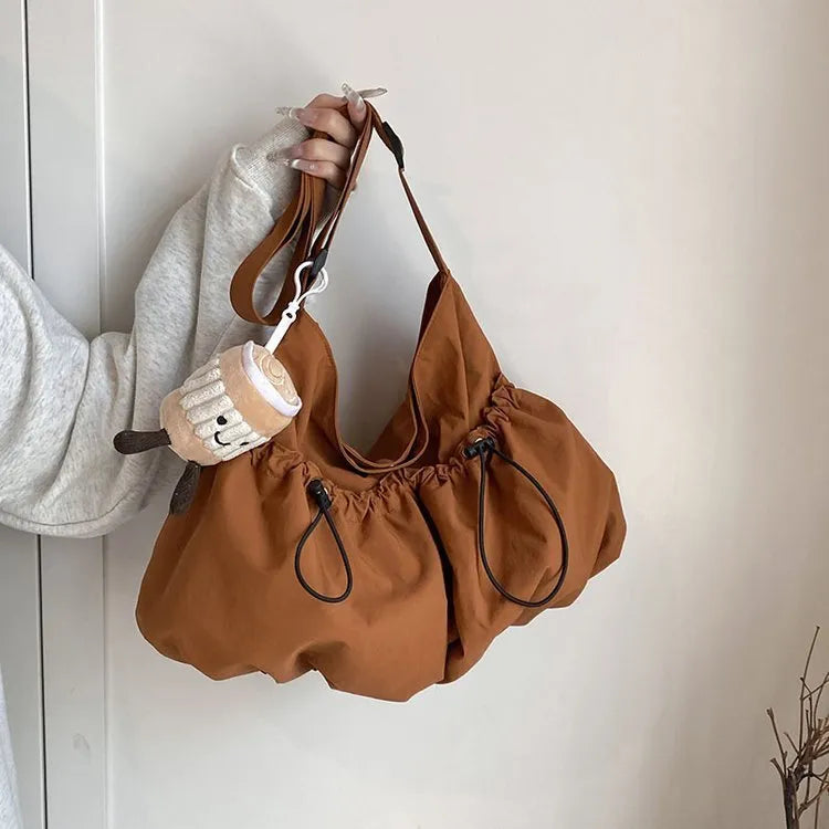 Ultra-light pleated green crossbody cloth bag lying flat, showing its split pocket and foldable design.