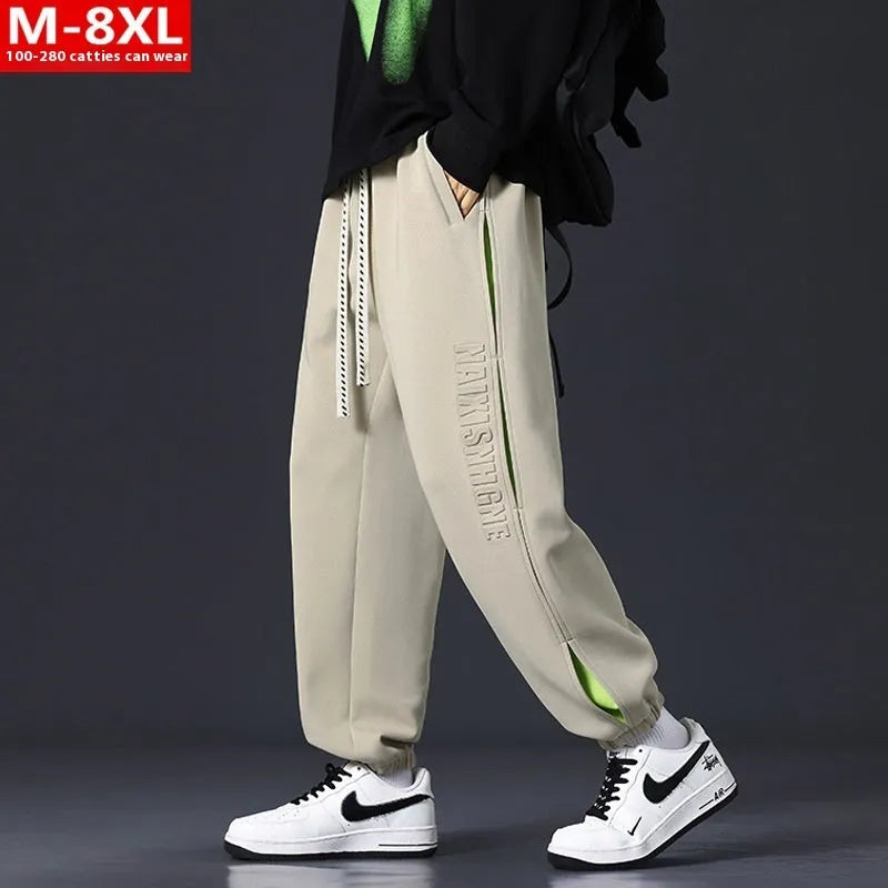 Men's loose grey green cotton trousers with ankle banding and stitching print detail on the leg.