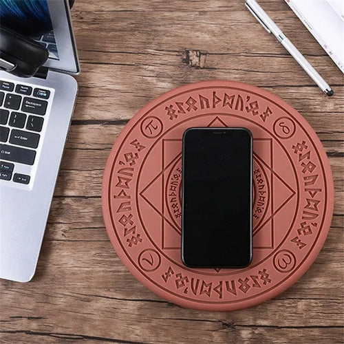 Black 10W fast wireless phone charger with glowing magic array pattern on a desk.