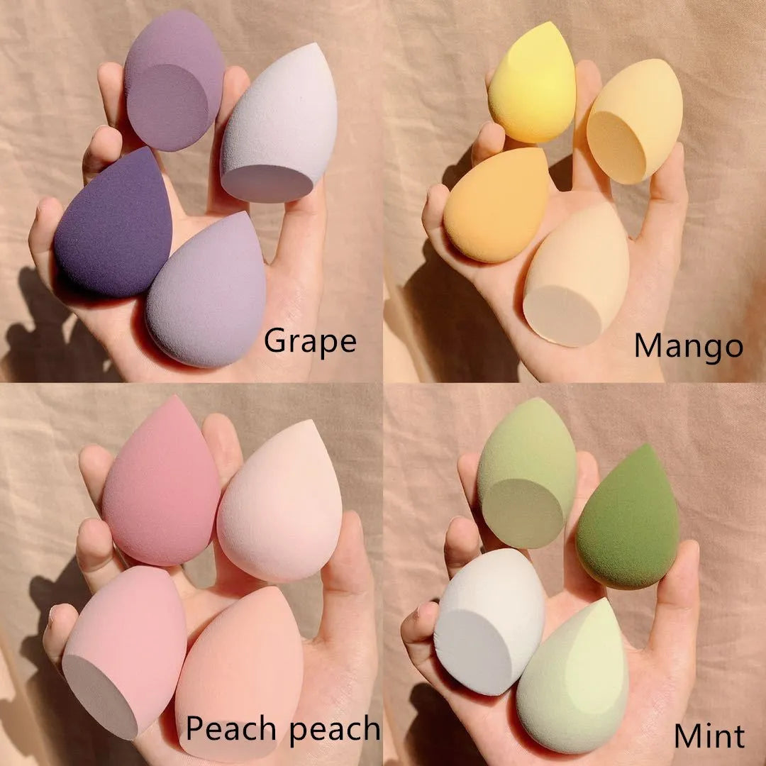 Four makeup sponge eggs in colours grape, mango, mint, and peach on a white background.