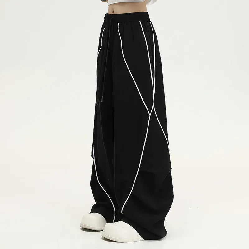 Black and white striped wide-leg hip hop sports trousers with pleats, shown laid flat.