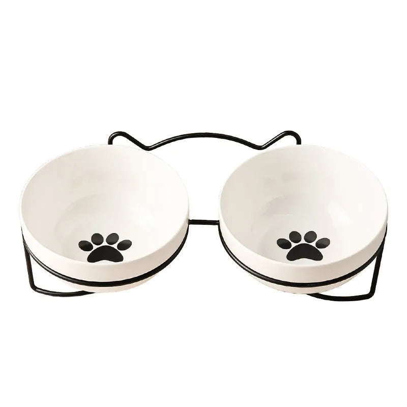 White ceramic pet bowl with cat paw design on a black metal stand with cat ear details.