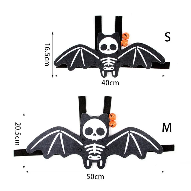 Black cat wearing an orange felt batwing Halloween costume with bell attachment.