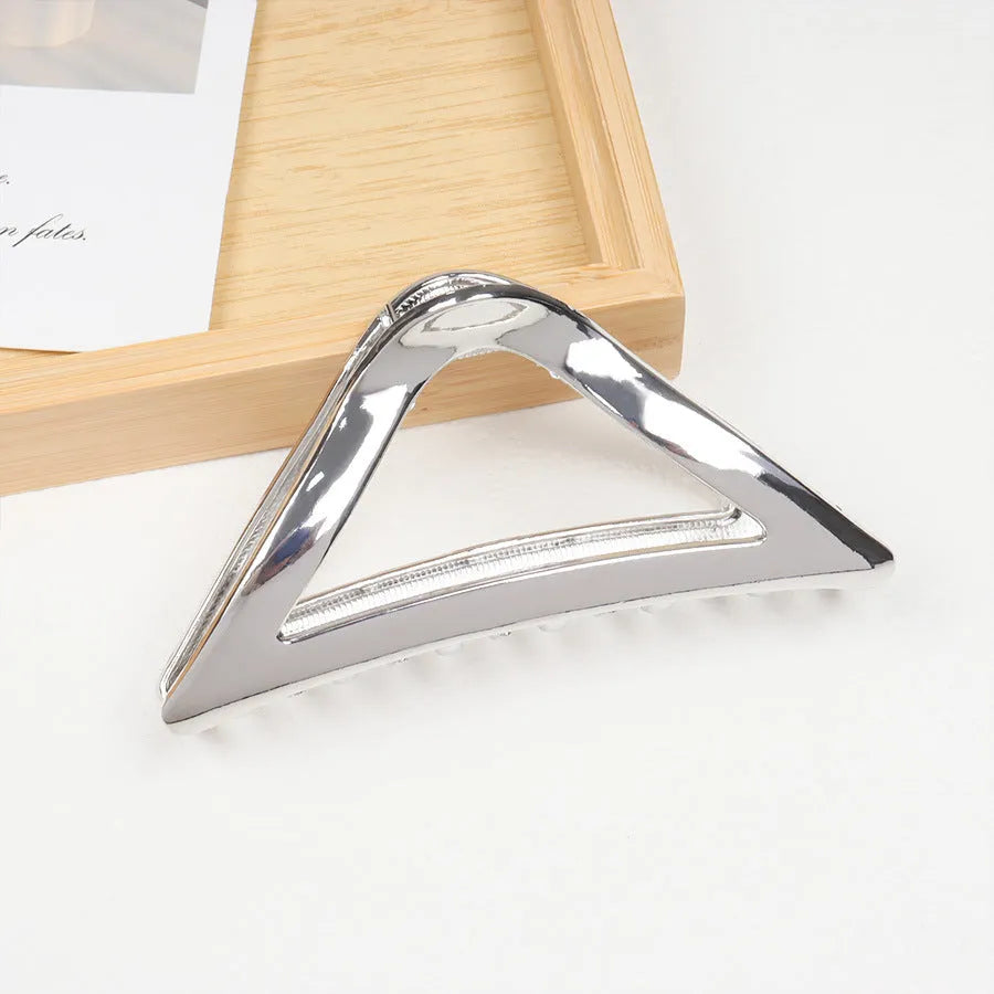 Assortment of silver metal hair claw barrettes with various designs including bows, pearls, and geometric shapes.
