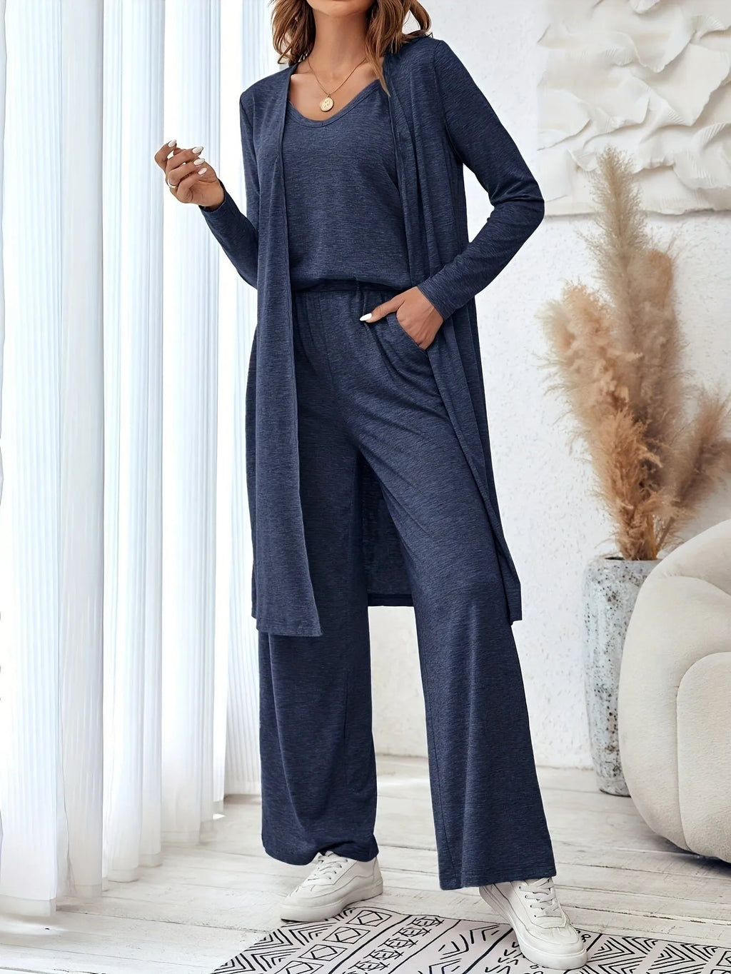 Blue women's three-piece suit featuring cardigan trousers, a long-sleeve top, and suspenders on a hanger.
