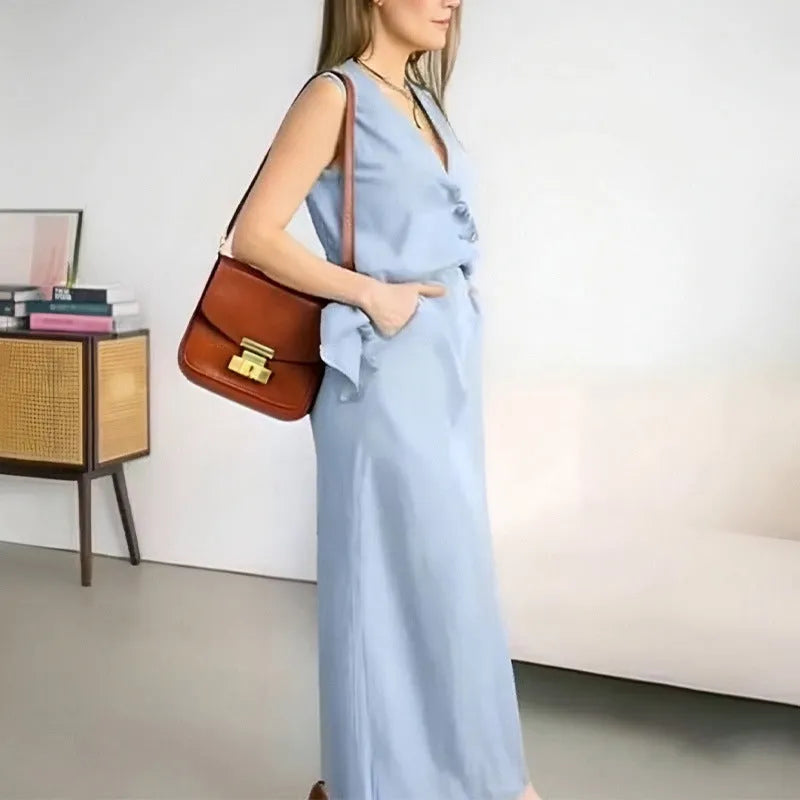 A woman wearing a blue sleeveless top and long matching skirt, a casual two-piece polyester suit.