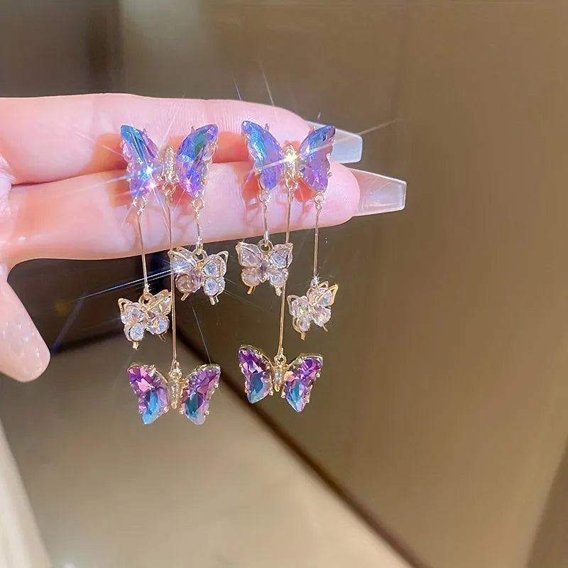 Silver electroplated alloy drop earrings with a blue purple butterfly charm and crystal flower details on a tassel.