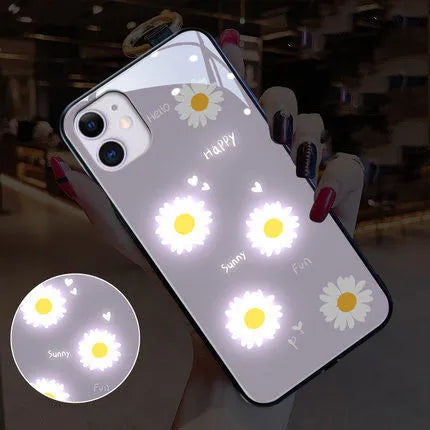 White daisy design voice-activated luminous TPU case for Apple iPhone on a table.