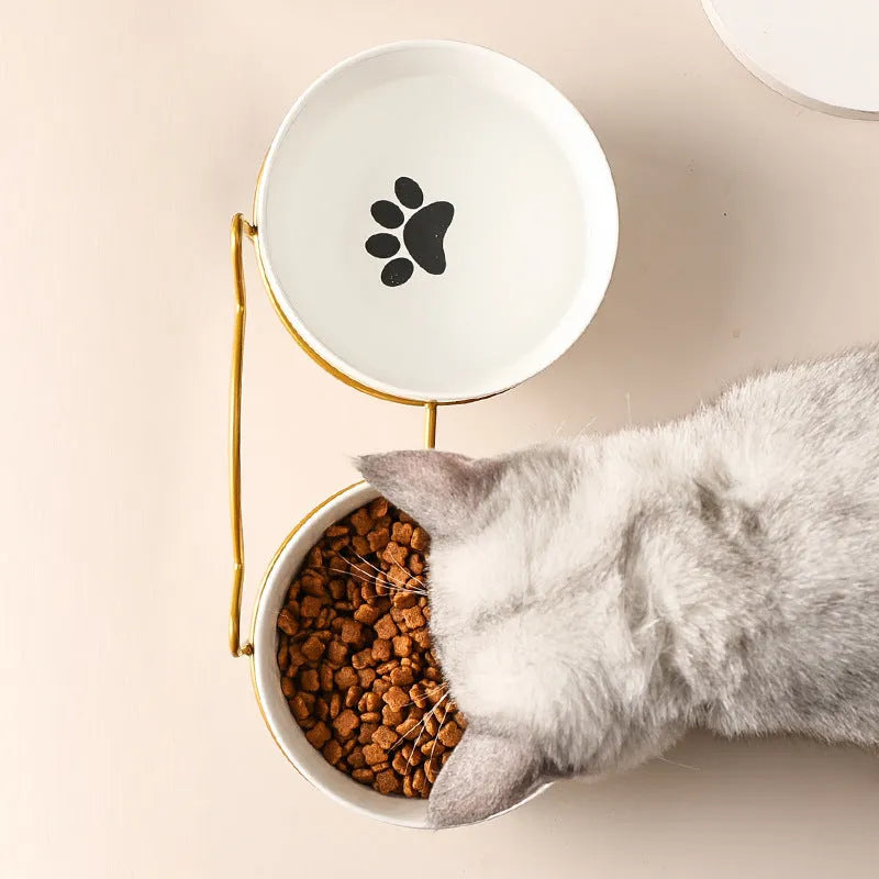White ceramic pet bowl with cat paw design on a black metal stand with cat ear details.
