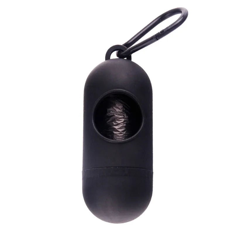 Compact black dog poop bag holder with Velcro strap and metal side hook, shown next to a roll of waste bags.