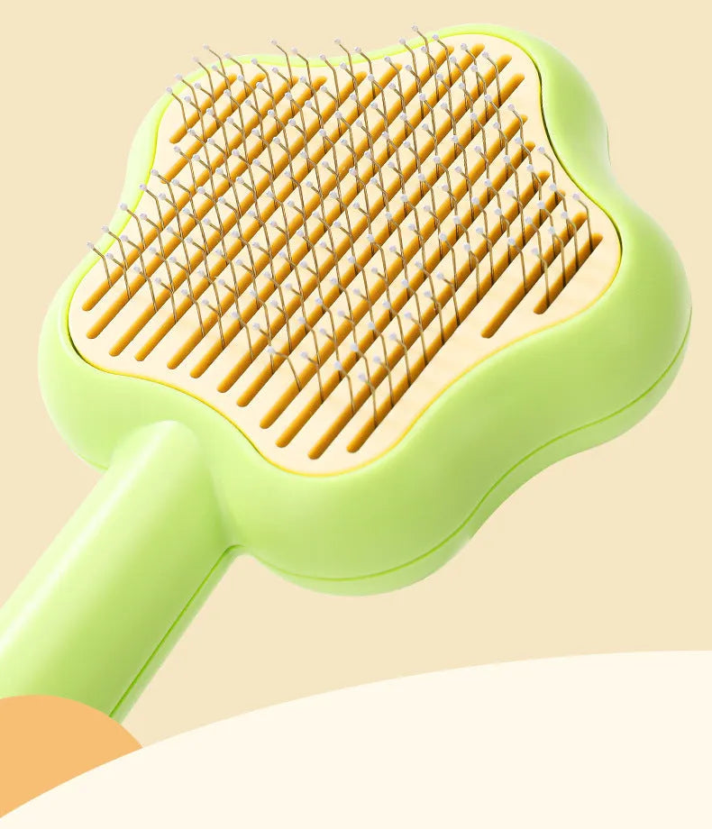 Green self-cleaning cat comb with stainless steel needle pins on a white background