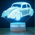 Colourful 3D LED desk lamp with black base and acrylic shade on wooden desk