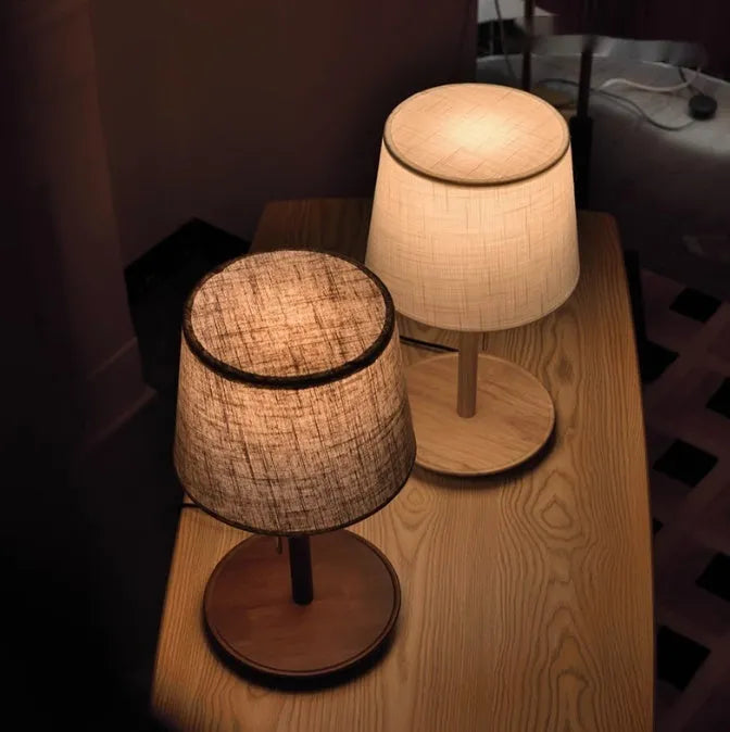 Walnut-colour solid wood desk lamp with a white fabric shade on a wooden table.