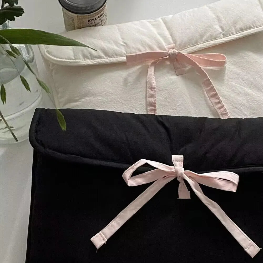 Women's black quilted laptop bag with ballet-style bow detail and striped pattern design