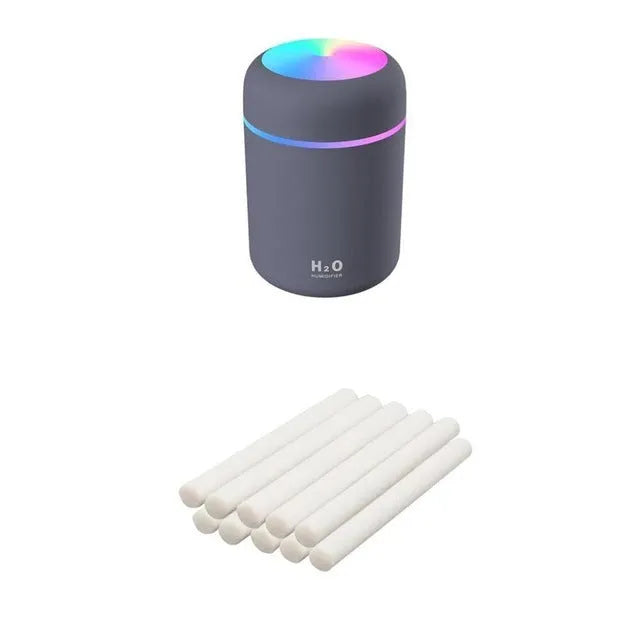 Pink USB desktop humidifier with coloured lights and water tank on a wooden desk