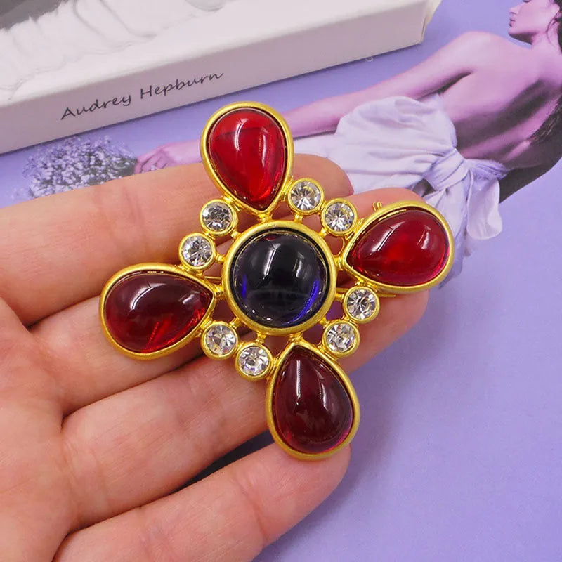 Close-up of a medieval-style baroque cross brooch with crystal decoration on a metal base.