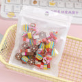 50 colourful cartoon mini erasers in shapes of fruits, animals, and cakes, displayed next to a pearlescent film bag.